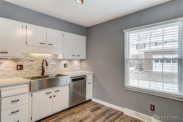 kitchen featuring sink, dishwasher, white cabinetry, backsplash, and light hardwood / wood-style floors