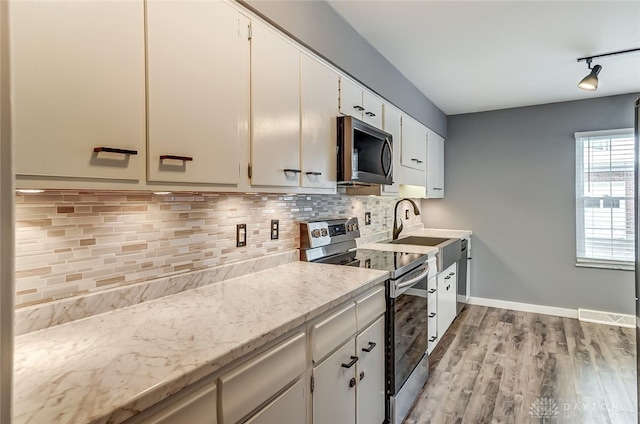 kitchen featuring stainless steel appliances, light wood-type flooring, white cabinets, and backsplash