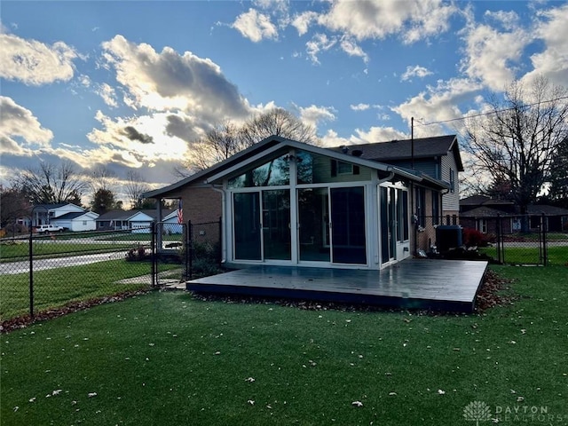 back of house featuring a wooden deck, a sunroom, and a lawn