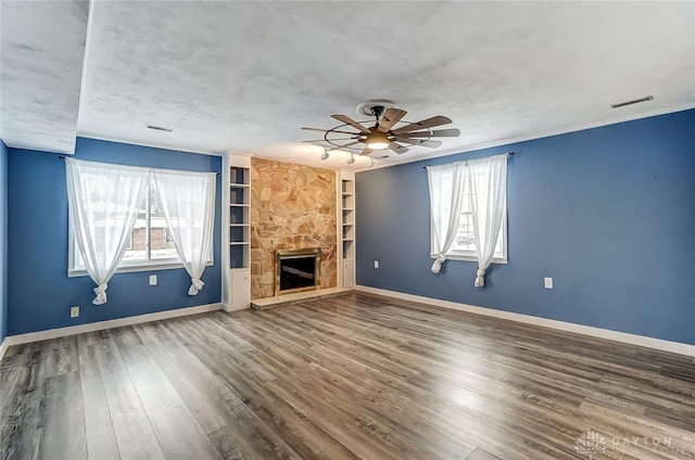 unfurnished living room featuring ceiling fan, wood-type flooring, a fireplace, and built in features