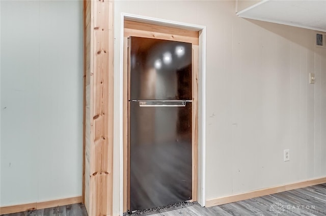 room details featuring wood-type flooring and black refrigerator