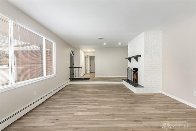 unfurnished living room featuring a baseboard heating unit, light hardwood / wood-style floors, and a brick fireplace