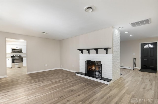 unfurnished living room featuring a baseboard radiator, light wood-type flooring, and a fireplace