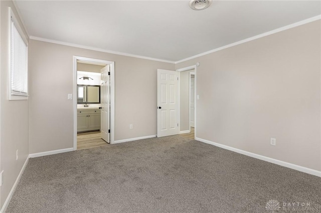 unfurnished bedroom featuring light carpet, sink, crown molding, and ensuite bathroom