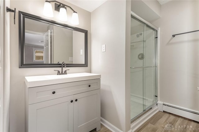 bathroom with vanity, a baseboard heating unit, a shower with shower door, and hardwood / wood-style floors