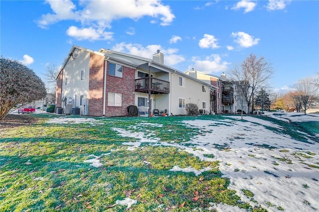 back of property featuring a balcony, a yard, and central air condition unit