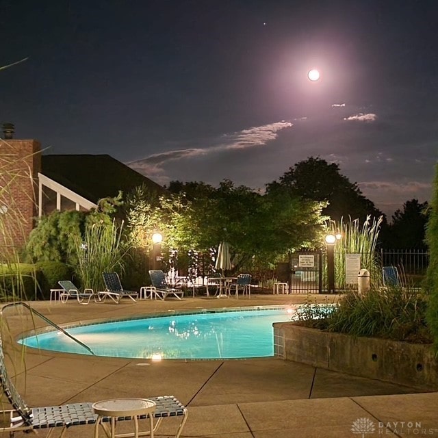 pool at twilight with a patio area