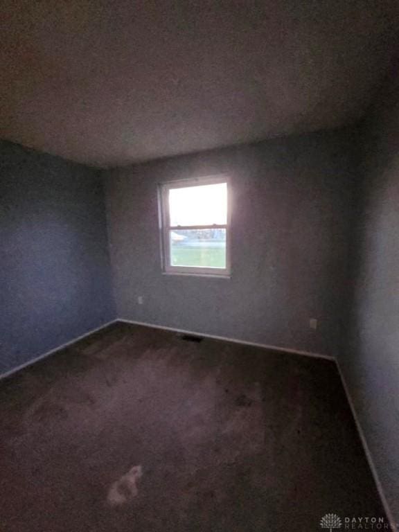 spare room featuring dark carpet