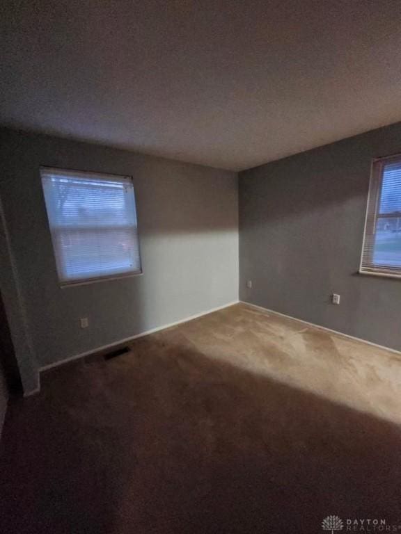 carpeted empty room with a textured ceiling