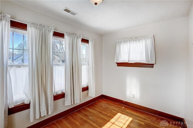 empty room with wood-type flooring and a textured ceiling