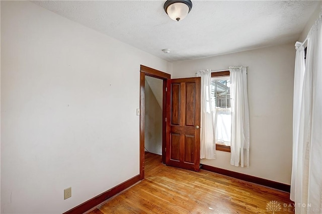 empty room with light hardwood / wood-style flooring and a textured ceiling