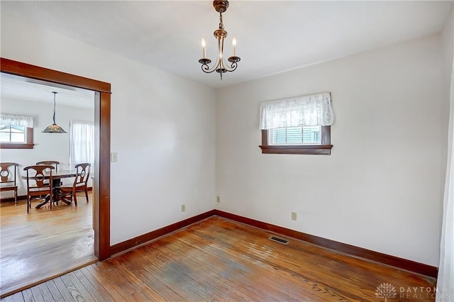 unfurnished room featuring hardwood / wood-style floors and a chandelier