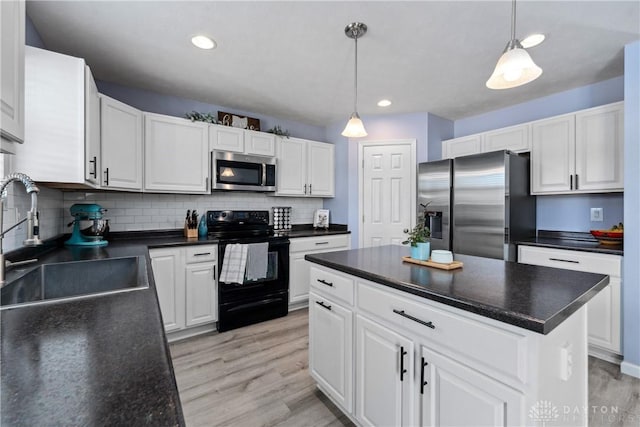 kitchen with sink, white cabinetry, hanging light fixtures, stainless steel appliances, and a kitchen island