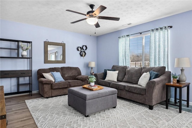 living room featuring ceiling fan, wood-type flooring, and a textured ceiling