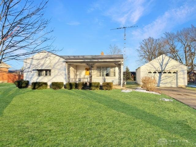 single story home with a garage, covered porch, and a front lawn