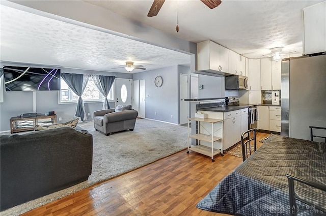 living room featuring ceiling fan, light hardwood / wood-style floors, and a textured ceiling