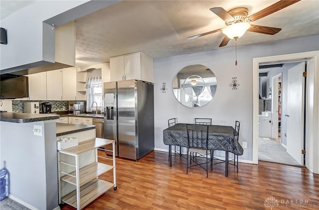 kitchen featuring sink, white cabinetry, backsplash, stainless steel appliances, and wood-type flooring