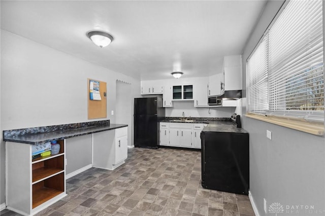 kitchen featuring white cabinetry, sink, and black fridge