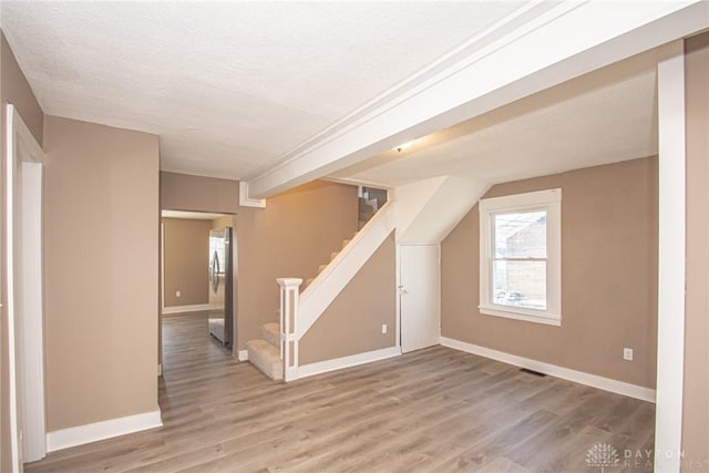 additional living space featuring hardwood / wood-style flooring and a textured ceiling