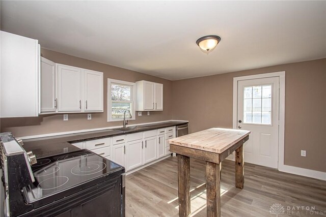 kitchen with white cabinetry, light hardwood / wood-style floors, sink, and electric range