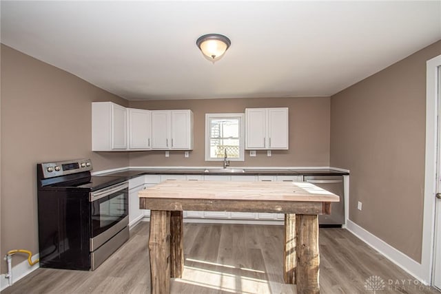 kitchen with stainless steel appliances, white cabinetry, sink, and light hardwood / wood-style floors