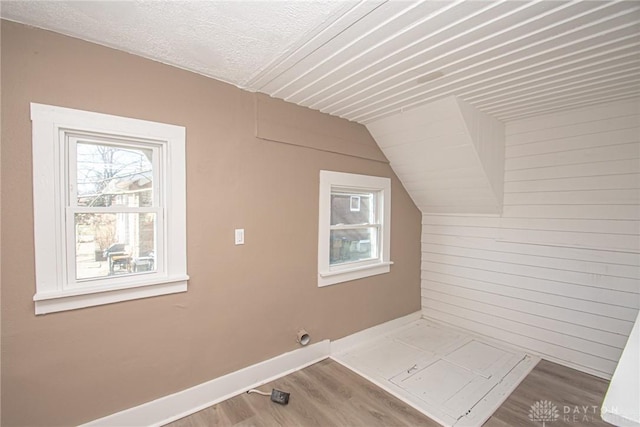 additional living space with wood-type flooring and vaulted ceiling