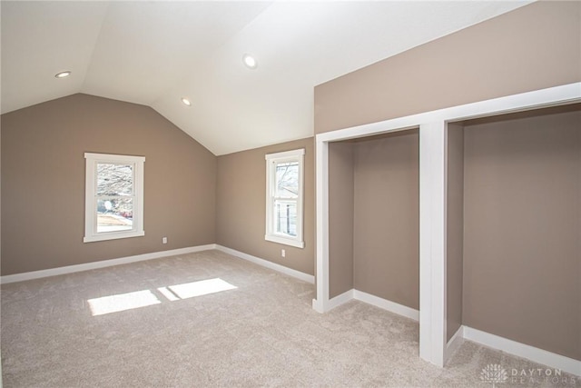 unfurnished bedroom featuring lofted ceiling and light carpet