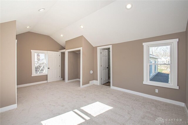 additional living space featuring vaulted ceiling and light colored carpet