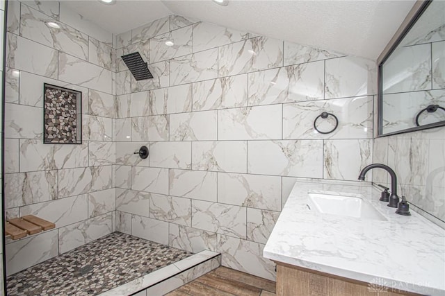 bathroom featuring vanity, lofted ceiling, and a tile shower