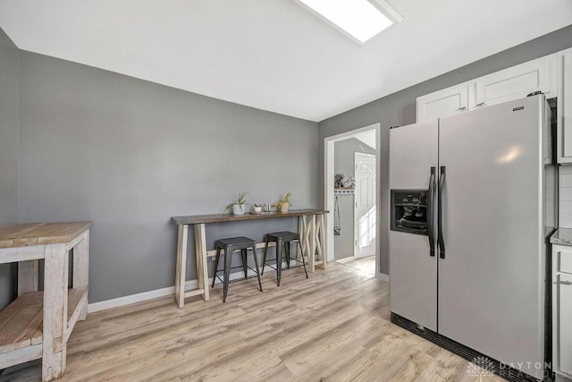 kitchen featuring white cabinetry, light wood-type flooring, and stainless steel refrigerator with ice dispenser