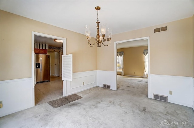 carpeted empty room featuring a chandelier