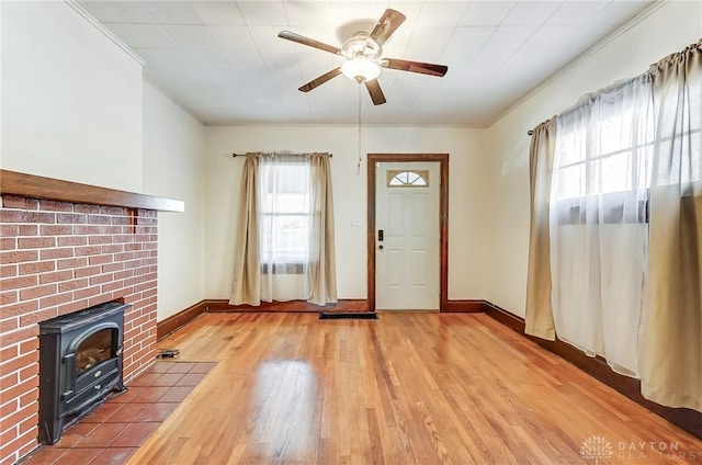 foyer entrance featuring ornamental molding, a wood stove, hardwood / wood-style floors, and ceiling fan