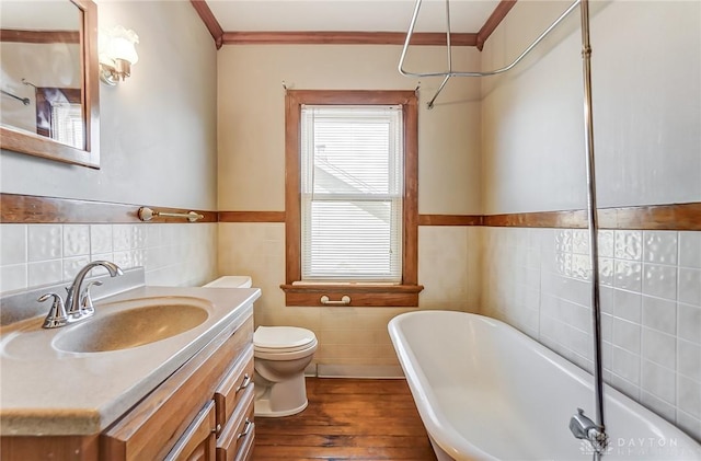 bathroom with crown molding, a bathing tub, vanity, wood-type flooring, and toilet