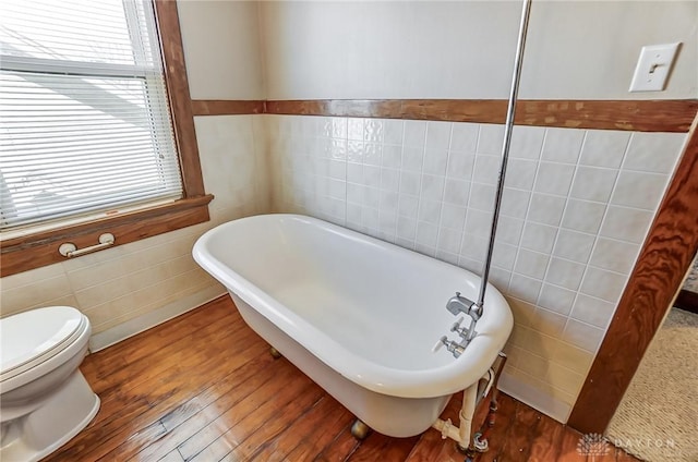 bathroom featuring wood-type flooring, tile walls, a bathtub, and toilet