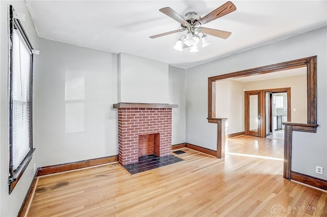 unfurnished living room featuring a brick fireplace, a wealth of natural light, light hardwood / wood-style flooring, and ceiling fan