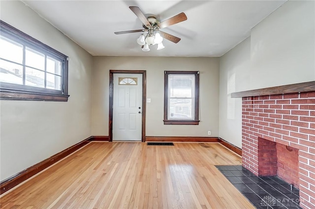 entryway with hardwood / wood-style flooring, ceiling fan, and a fireplace