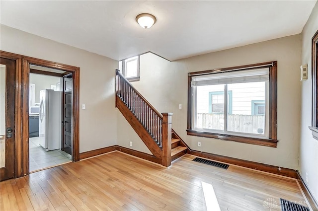 unfurnished room with a healthy amount of sunlight and light hardwood / wood-style floors