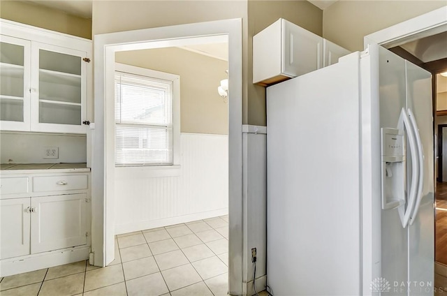 kitchen with white cabinetry, white fridge with ice dispenser, and light tile patterned floors