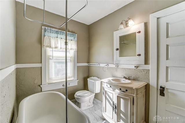 bathroom featuring vanity, a tub to relax in, and toilet