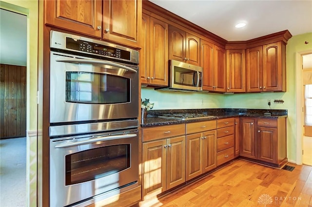 kitchen featuring light hardwood / wood-style flooring, stainless steel appliances, and dark stone counters