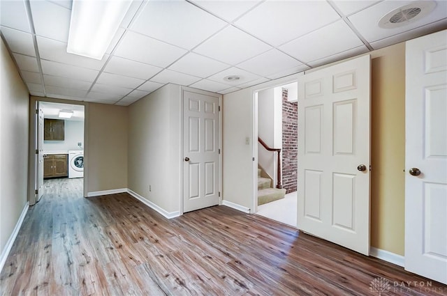 interior space featuring washer / dryer, a paneled ceiling, and light hardwood / wood-style flooring