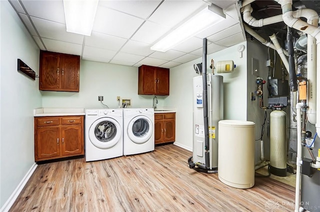 washroom with sink, water heater, cabinets, independent washer and dryer, and light wood-type flooring