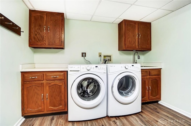 washroom with cabinets, hardwood / wood-style flooring, sink, and washing machine and clothes dryer