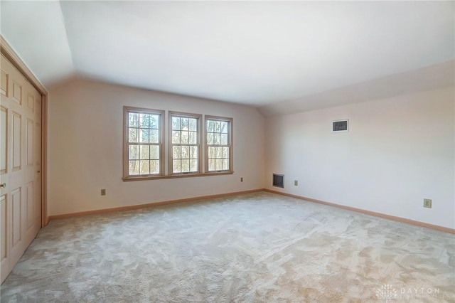 carpeted spare room with vaulted ceiling