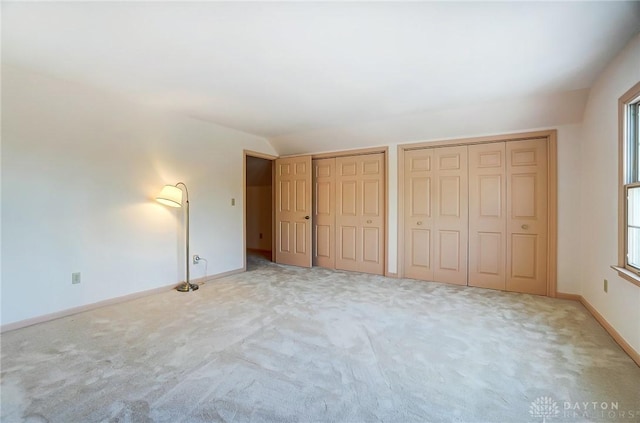 unfurnished bedroom with light colored carpet and two closets