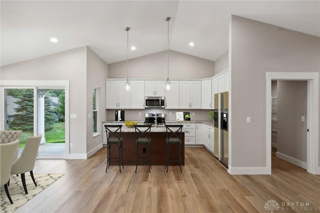 kitchen with pendant lighting, a breakfast bar area, appliances with stainless steel finishes, a center island, and white cabinets