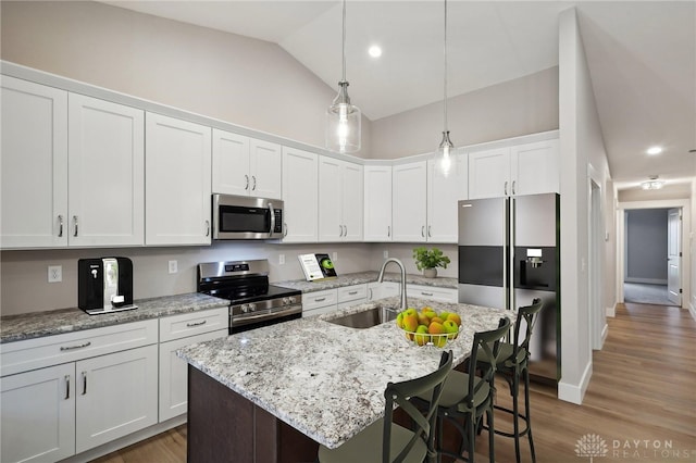 kitchen featuring stainless steel appliances, white cabinetry, sink, and a center island with sink