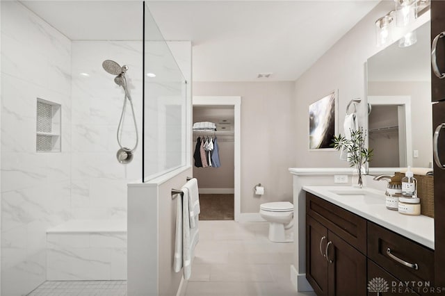 bathroom featuring vanity, toilet, and tiled shower