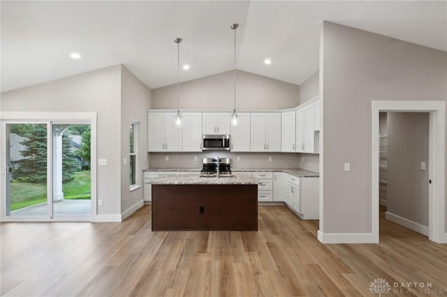 kitchen featuring hanging light fixtures, appliances with stainless steel finishes, a kitchen island with sink, and white cabinets