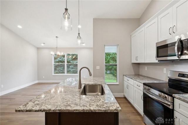 kitchen featuring sink, decorative light fixtures, stainless steel appliances, and a center island with sink